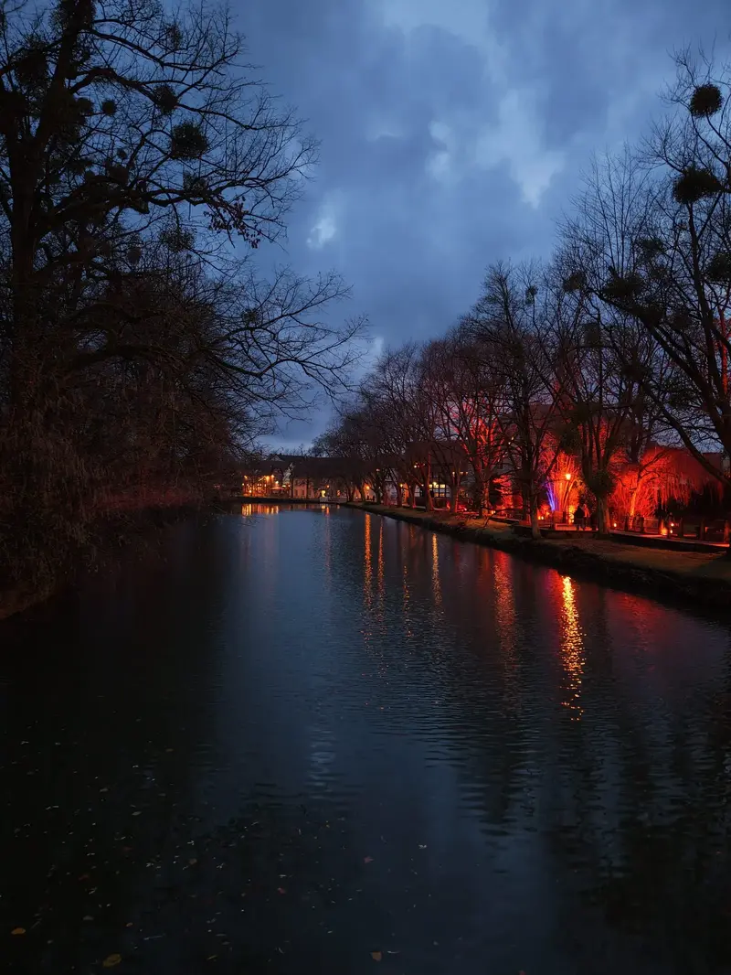 Original-Drohnenaufnahme eines beleuchteten Flusslaufs am Abend (Hochformat)